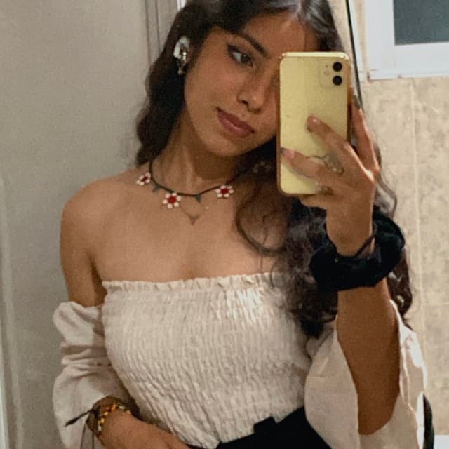 Persona con auriculares, haciéndose una foto frente a un espejo con su smartphone.